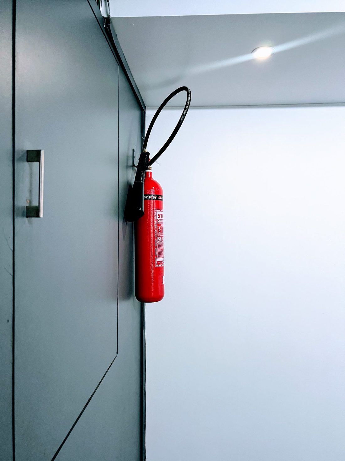 Röd brandsläckare monterad på vägg
